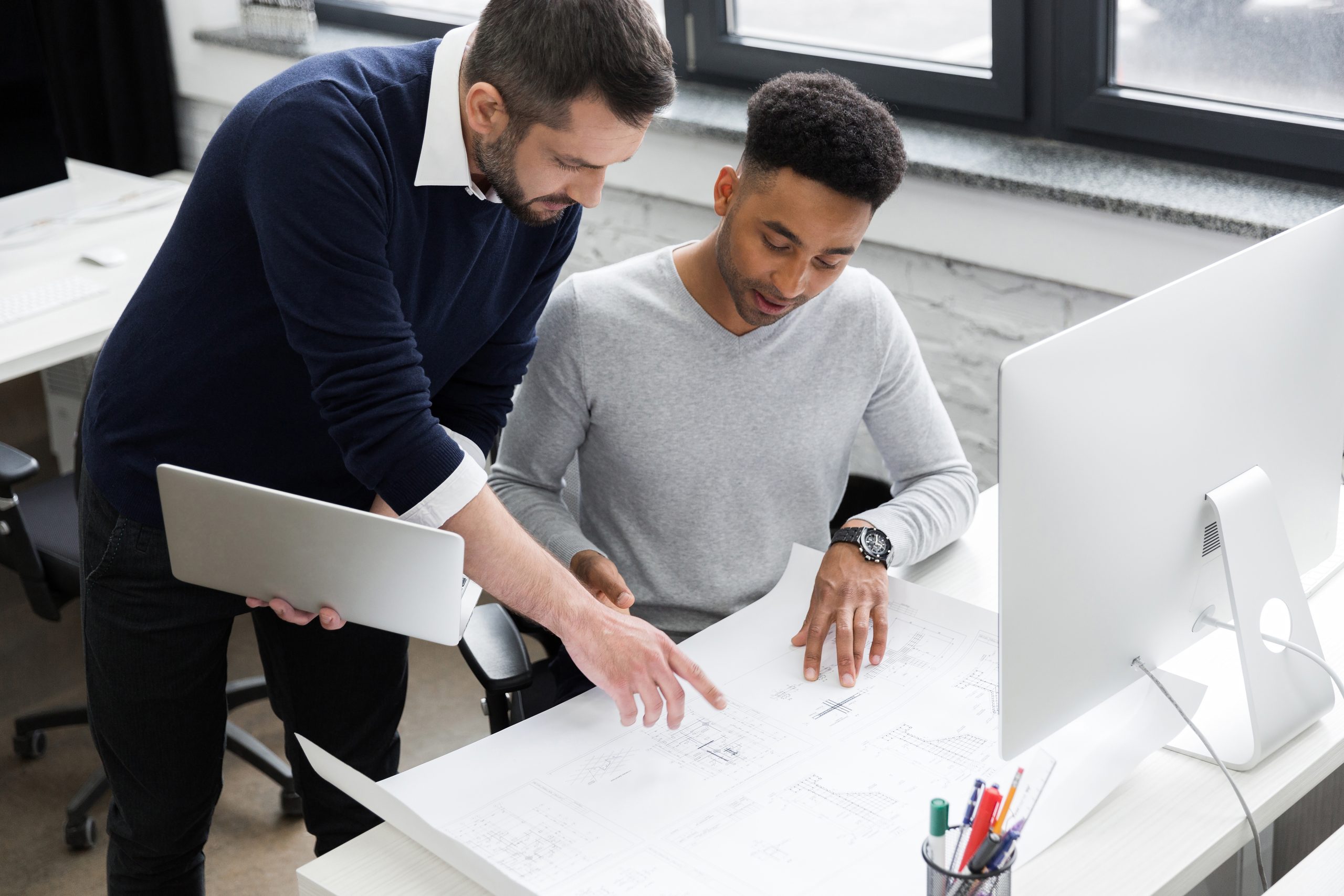 two smiling male office workers working with laptop scaled